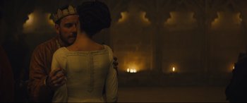 Movie still from “Macbeth” (2015), directed by Justin Kurzel – A man and a woman standing next to each other in front of candles; Medium shot, Over the shoulder angle