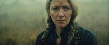 Movie still from “Macbeth” (2015), directed by Justin Kurzel – An older woman with long blonde hair wearing a black shirt; Close Up shot, Over the shoulder angle