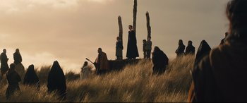 Movie still from “Macbeth” (2015), directed by Justin Kurzel – A group of people standing on top of a grass covered hill; Extreme Wide shot, Low angle