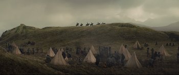Movie still from “Macbeth” (2015), directed by Justin Kurzel – A group of people sitting around tents on top of a hill; Extreme Wide shot, High angle