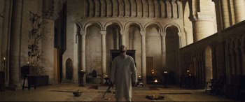 Movie still from “Macbeth” (2015), directed by Justin Kurzel – A man standing in front of a fireplace holding a sword; Wide shot, Low angle
