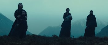 Movie still from “Macbeth” (2015), directed by Justin Kurzel – A woman standing on top of a hill talking on a cell phone; Wide shot, Low angle