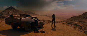 Movie still from “Mad Max: Fury Road” (2015), directed by George Miller – A man standing next to an abandoned car in the middle of the desert; Wide shot, High angle