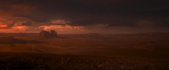 Movie still from “Mad Max: Fury Road” (2015), directed by George Miller – A view of a desert landscape with a sunset in the background; Extreme Wide shot, High angle