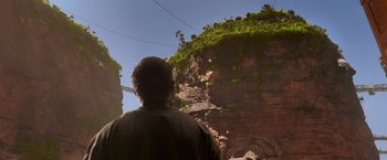 Movie still from “Mad Max: Fury Road” (2015), directed by George Miller – A man standing in front of a cliff; Extreme Wide shot, Over the shoulder angle