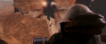 Movie still from “Mad Max: Fury Road” (2015), directed by George Miller – A man standing in front of a tunnel with a crane; Extreme Wide shot, High angle