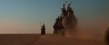 Movie still from “Mad Max: Fury Road” (2015), directed by George Miller – A group of people riding on the back of a train; Extreme Wide shot, Low angle