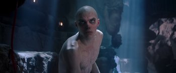 Movie still from “Mad Max: Fury Road” (2015), directed by George Miller – A man with a shaved head is looking at the camera; Medium shot, Low angle