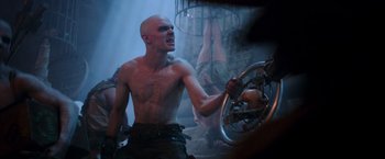 Movie still from “Mad Max: Fury Road” (2015), directed by George Miller – A man with a shaved bald head is holding a steering wheel; Medium shot, Low angle