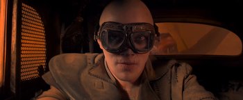 Movie still from “Mad Max: Fury Road” (2015), directed by George Miller – A man wearing goggles and a tan jacket; Close Up shot, Low angle