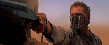 Movie still from “Mad Max: Fury Road” (2015), directed by George Miller – A man with a knife in his hand and a mask on his face; Close Up shot, Over the shoulder angle