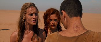 Movie still from “Mad Max: Fury Road” (2015), directed by George Miller – A group of people standing next to each other in the desert; Close Up shot, Over the shoulder angle