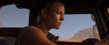 Movie still from “Mad Max: Fury Road” (2015), directed by George Miller – A person with a gun in front of a window; Close Up shot, Low angle