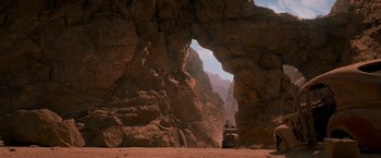 Movie still from “Mad Max: Fury Road” (2015), directed by George Miller – A vehicle is driving through a rock tunnel; Extreme Wide shot, Low angle
