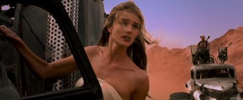 Movie still from “Mad Max: Fury Road” (2015), directed by George Miller – A beautiful woman with long blonde hair standing in front of an open door; Close Up shot, Low angle