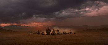 Movie still from “Mad Max: Fury Road” (2015), directed by George Miller – A group of tanks driving down a dirt road under a cloudy sky; Extreme Wide shot, High angle