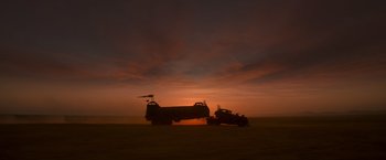 Movie still from “Mad Max: Fury Road” (2015), directed by George Miller – A truck is pulling a trailer in the middle of a field; Extreme Wide shot, Low angle