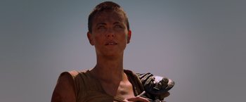 Movie still from “Mad Max: Fury Road” (2015), directed by George Miller – A person holding a skateboard; Close Up shot, Low angle