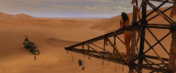 Movie still from “Mad Max: Fury Road” (2015), directed by George Miller – A man standing on top of a wooden structure in the middle of the desert; Extreme Wide shot, High angle