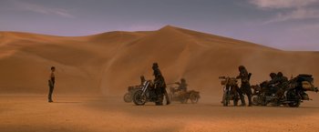Movie still from “Mad Max: Fury Road” (2015), directed by George Miller – A group of people riding motorcycles in the desert; Extreme Wide shot, High angle