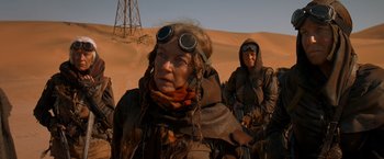 Movie still from “Mad Max: Fury Road” (2015), directed by George Miller – A woman with goggles on and a man with goggles on in the desert; Medium shot, Low angle