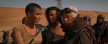 Movie still from “Mad Max: Fury Road” (2015), directed by George Miller – A group of people standing next to each other in the desert; Medium shot, Low angle