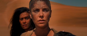 Movie still from “Mad Max: Fury Road” (2015), directed by George Miller – A person with dirt on their face; Close Up shot, Over the shoulder angle