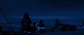 Movie still from “Mad Max: Fury Road” (2015), directed by George Miller – A group of people sitting on the beach at night; Wide shot, Low angle