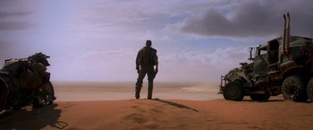 Movie still from “Mad Max: Fury Road” (2015), directed by George Miller – A man standing on top of a sandy beach looking out at the ocean; Extreme Wide shot, Low angle