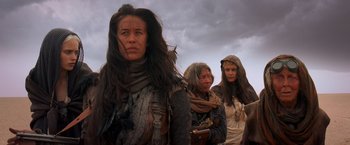 Movie still from “Mad Max: Fury Road” (2015), directed by George Miller – A group of women standing next to each other in a field; Medium shot, Low angle