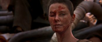 Movie still from “Mad Max: Fury Road” (2015), directed by George Miller – A person with blood all over their face; Close Up shot, Over the shoulder angle