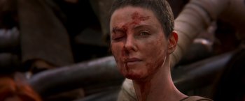 Movie still from “Mad Max: Fury Road” (2015), directed by George Miller – A person with blood on their face; Close Up shot, Over the shoulder angle