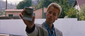 Movie still from “Memento” (2000), directed by Christopher Nolan – A man holding up an image of an animal; Close Up shot, Over the shoulder angle