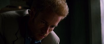 Movie still from “Memento” (2000), directed by Christopher Nolan – A person wearing a suit and tie; Close Up shot, Low angle