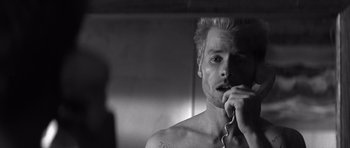 Movie still from “Memento” (2000), directed by Christopher Nolan – A black and white photo of a man in a mirror; Close Up shot, Low angle