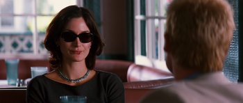 Movie still from “Memento” (2000), directed by Christopher Nolan – A woman wearing sunglasses is sitting next to a man; Close Up shot, Over the shoulder angle