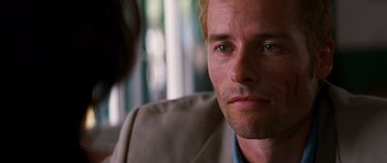 Movie still from “Memento” (2000), directed by Christopher Nolan – A person wearing a suit and tie; Close Up shot, Over the shoulder angle