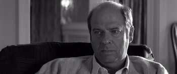 Movie still from “Memento” (2000), directed by Christopher Nolan – Black and white photograph of a man in a chair; Close Up shot, Over the shoulder angle