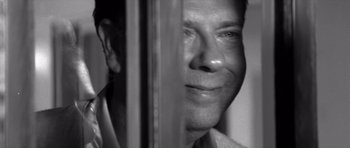 Movie still from “Memento” (2000), directed by Christopher Nolan – A black - and - white photo of a man looking out a window; Close Up shot, Over the shoulder angle