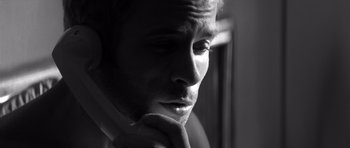 Movie still from “Memento” (2000), directed by Christopher Nolan – Black and white photograph of a man with his hand on his chin; Extreme Close Up shot, Low angle