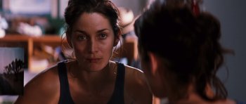 Movie still from “Memento” (2000), directed by Christopher Nolan – A woman looking at another woman in a dark room; Close Up shot, Over the shoulder angle