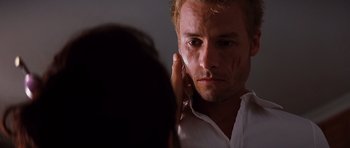 Movie still from “Memento” (2000), directed by Christopher Nolan – A man looking into a mirror while holding a cell phone to his ear; Close Up shot, Over the shoulder angle