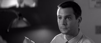 Movie still from “Memento” (2000), directed by Christopher Nolan – Black and white photograph of a man in a suit and tie; Close Up shot, Low angle