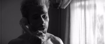 Movie still from “Memento” (2000), directed by Christopher Nolan – A man with a beard is sitting in front of a window; Close Up shot, Low angle