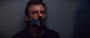 Movie still from “Memento” (2000), directed by Christopher Nolan – A man with duct tape over his mouth and nose; Close Up shot, High angle