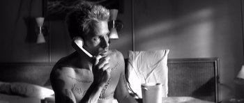 Movie still from “Memento” (2000), directed by Christopher Nolan – A man sitting on a bed talking on a phone; Close Up shot, Low angle