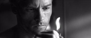 Movie still from “Memento” (2000), directed by Christopher Nolan – A man holding a candle; Extreme Close Up shot, Low angle