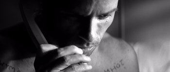 Movie still from “Memento” (2000), directed by Christopher Nolan – Black and white photograph of a man with his hand to his face; Extreme Close Up shot, Low angle