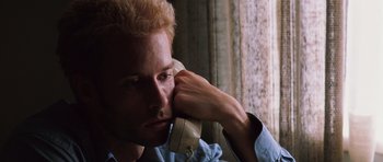 Movie still from “Memento” (2000), directed by Christopher Nolan – A man with blonde hair talking on a phone; Close Up shot, Low angle
