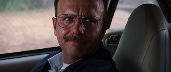 Movie still from “Memento” (2000), directed by Christopher Nolan – A person wearing glasses with a mustache; Close Up shot, Low angle